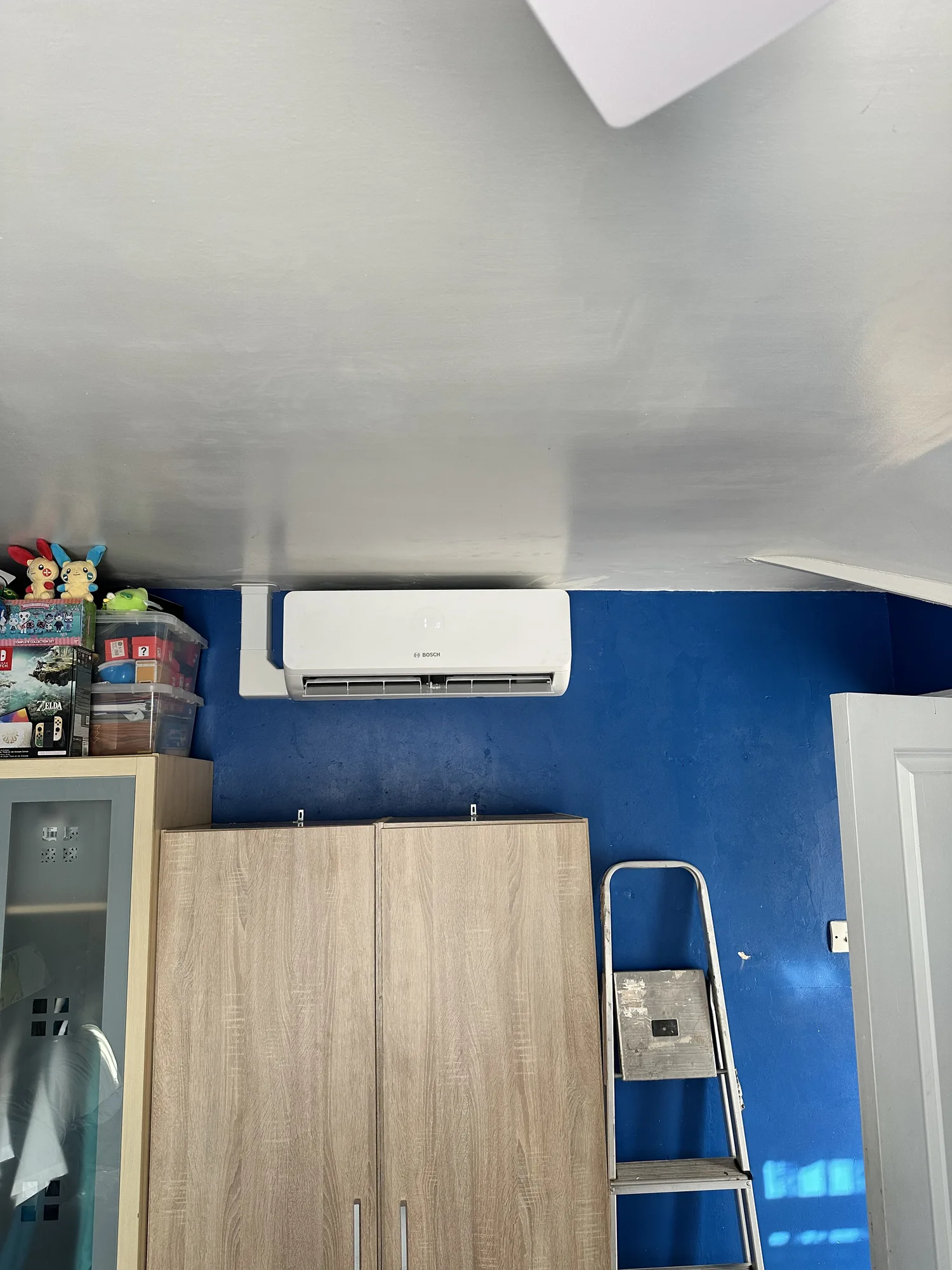 Wall-mounted air conditioning indoor split unit on a blue feature wall