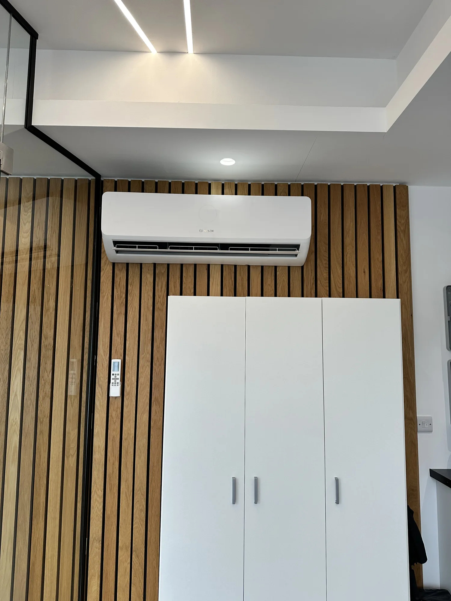 Wall-mounted air conditioning indoor split unit on a modern wood-slat wall