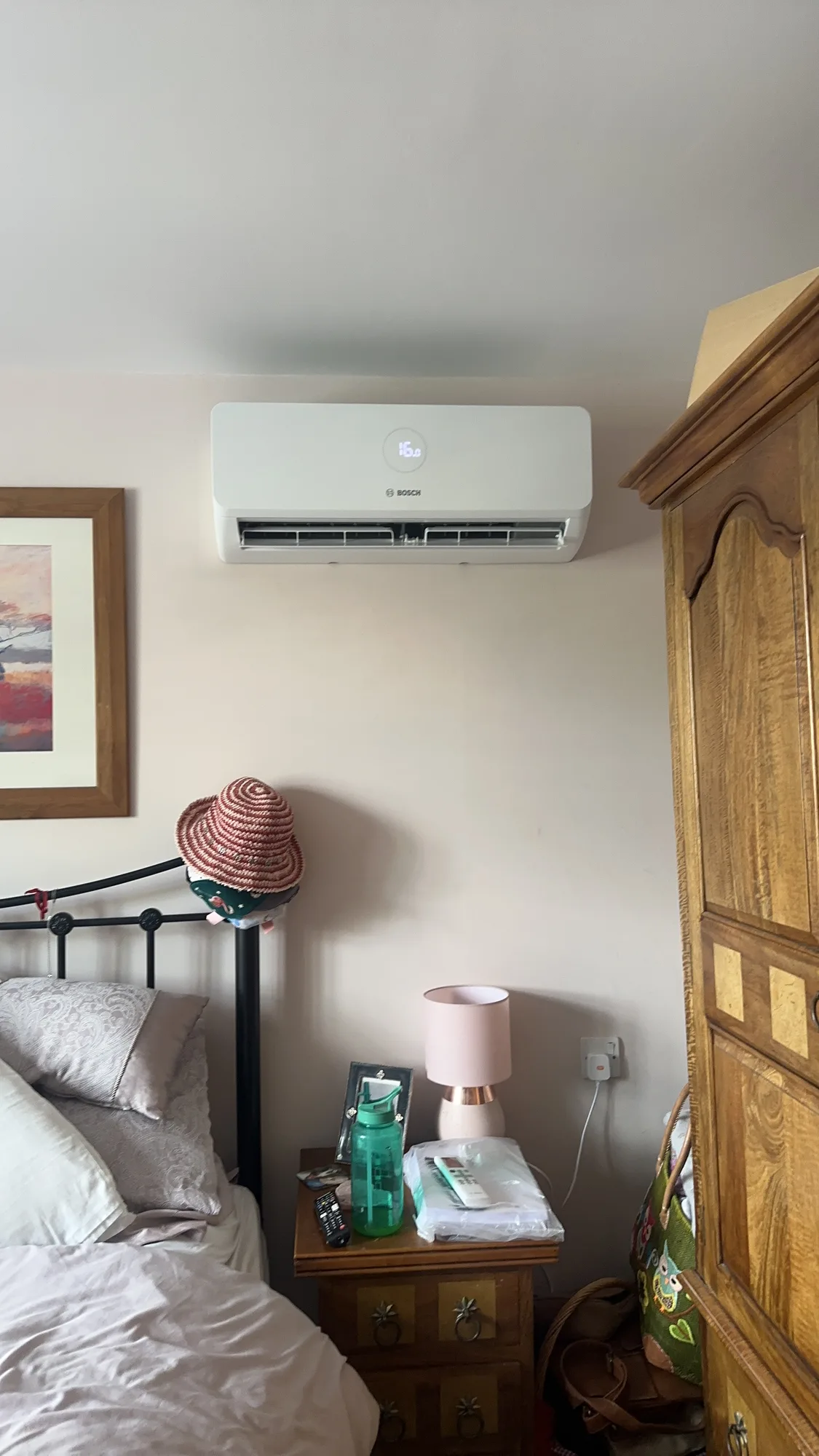 Wall-mounted air conditioning indoor split unit above a bedroom nightstand