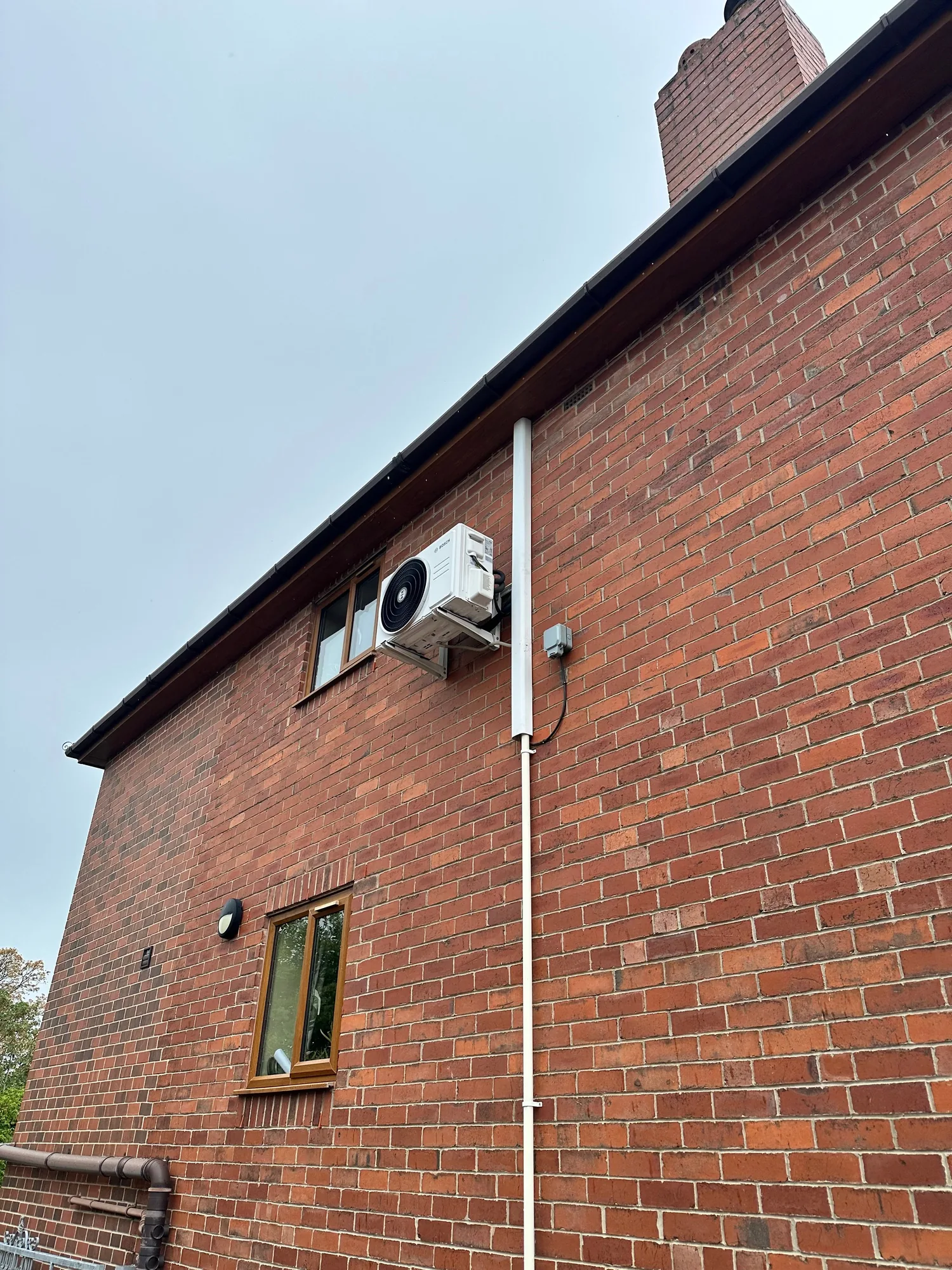 Air conditioning condenser mounted high on a brick wall