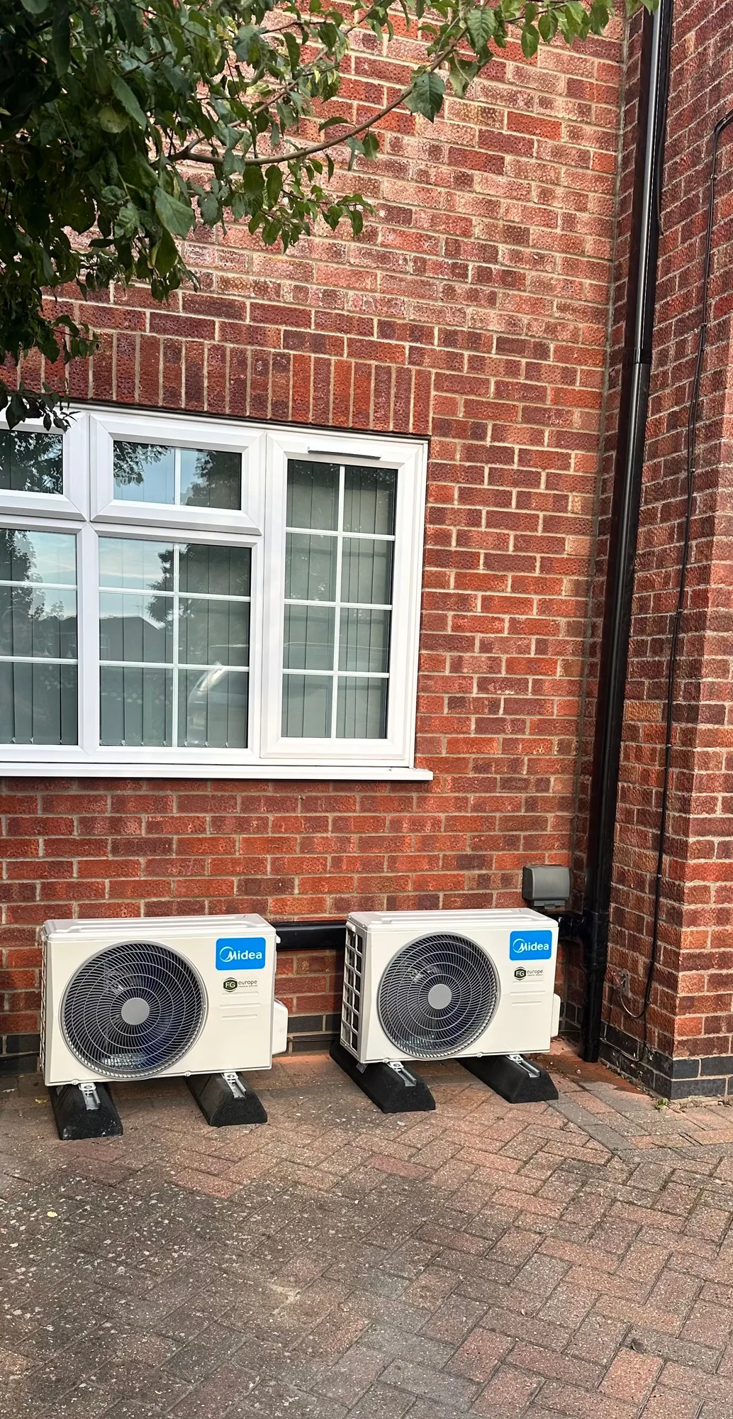 Two air conditioning condensers installed beneath a window