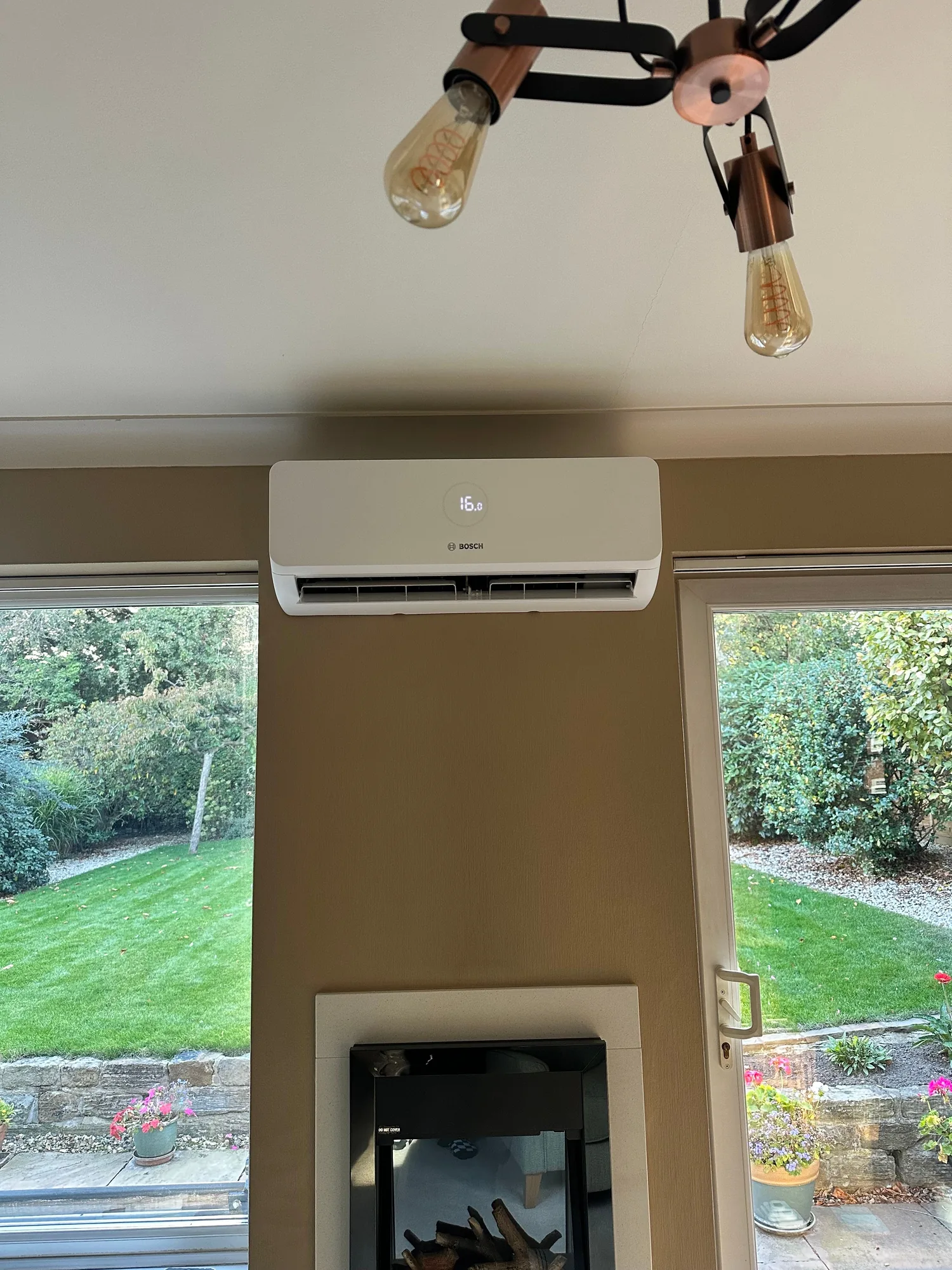 Bosch indoor air conditioning unit mounted above patio doors in a living room