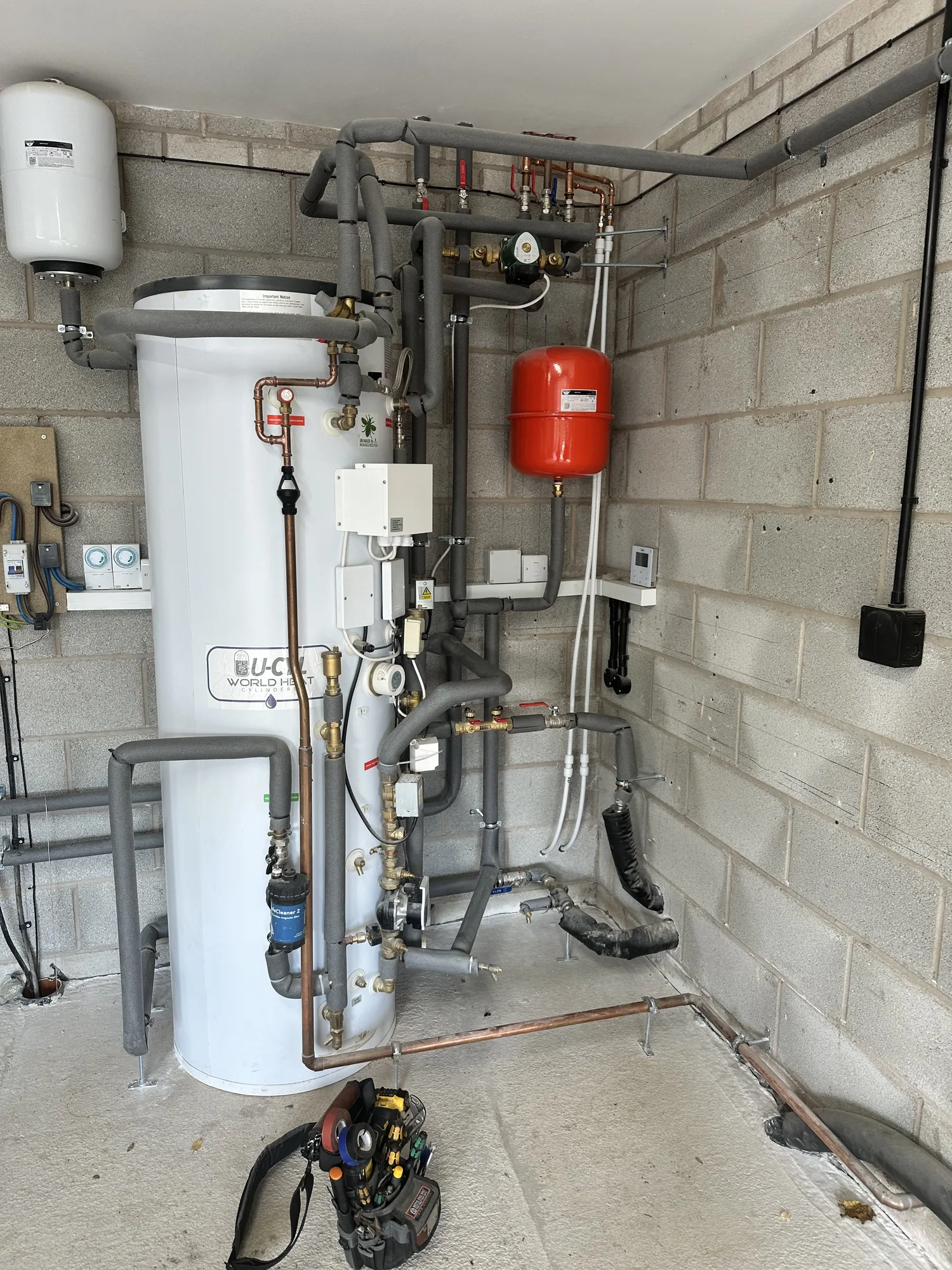 Unvented hot water cylinder with red expansion vessel and copper heating pipework