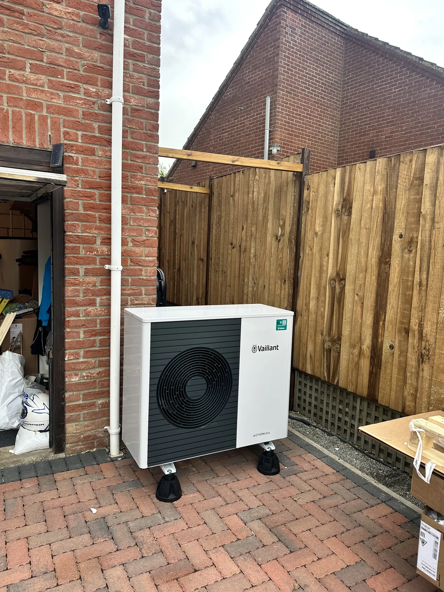 Vaillant aroTHERM air source heat pump outdoor unit beside a brick wall and fence