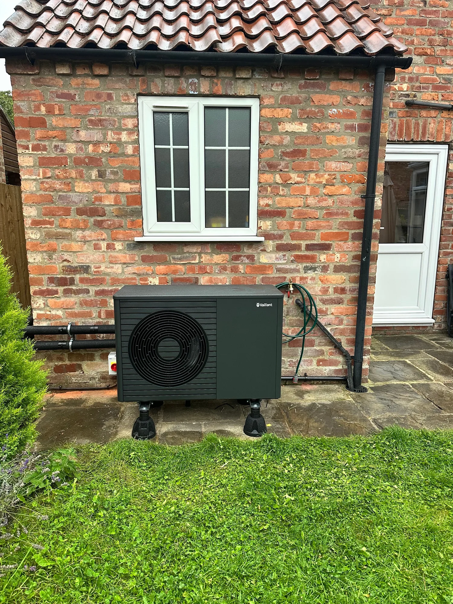Air source heat pump unit on a paved base in a garden