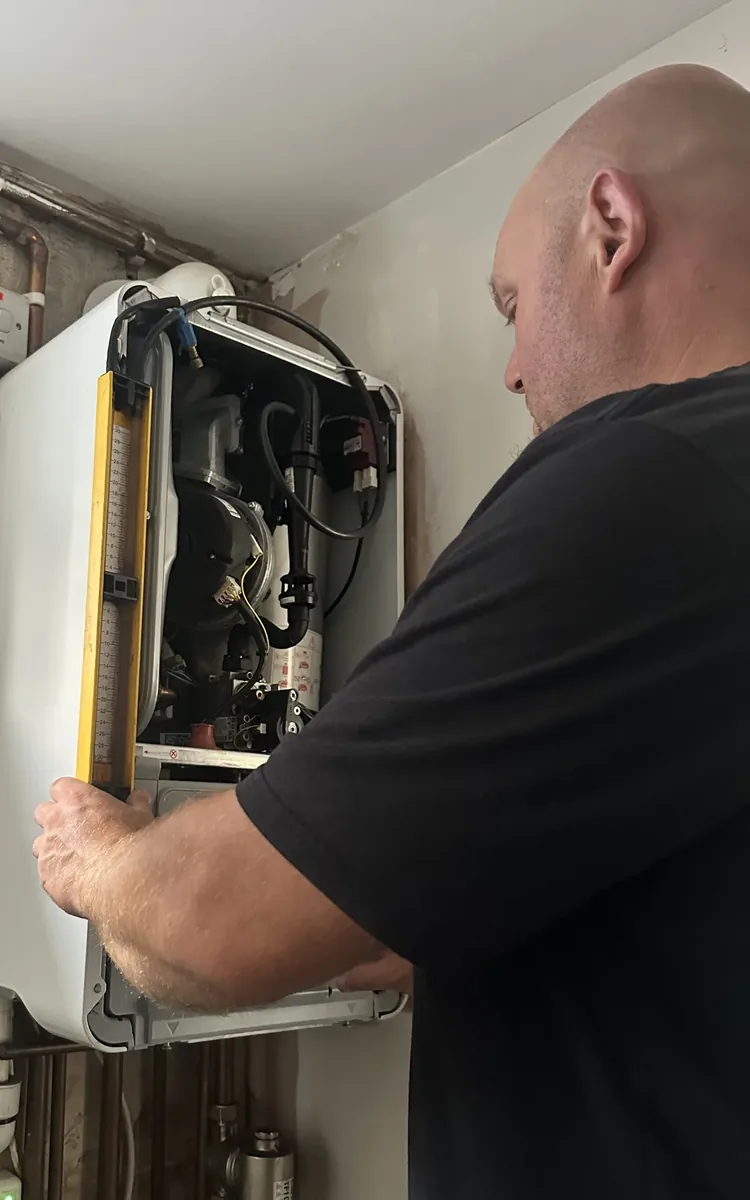 Matthew Stokes, owner of Fuzzy Duck PHC, servicing a gas boiler