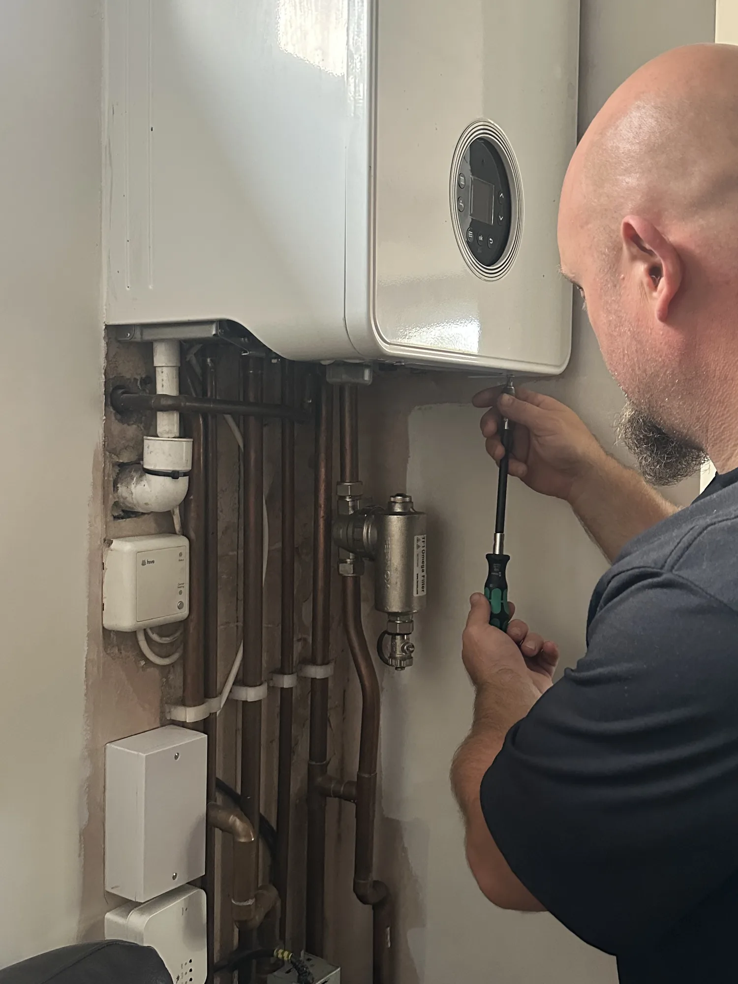 Fuzzy Duck PHC engineer servicing a wall-mounted gas boiler